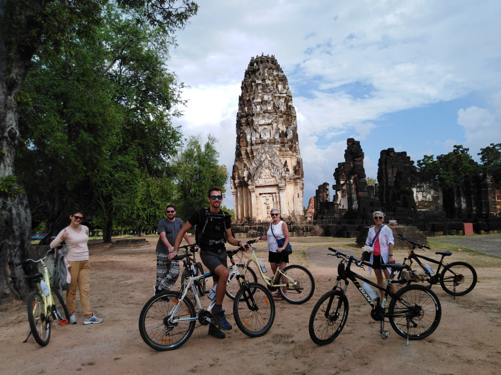 Cyclist riding through Sukhothai countryside with rice fields and Buddhist shrines