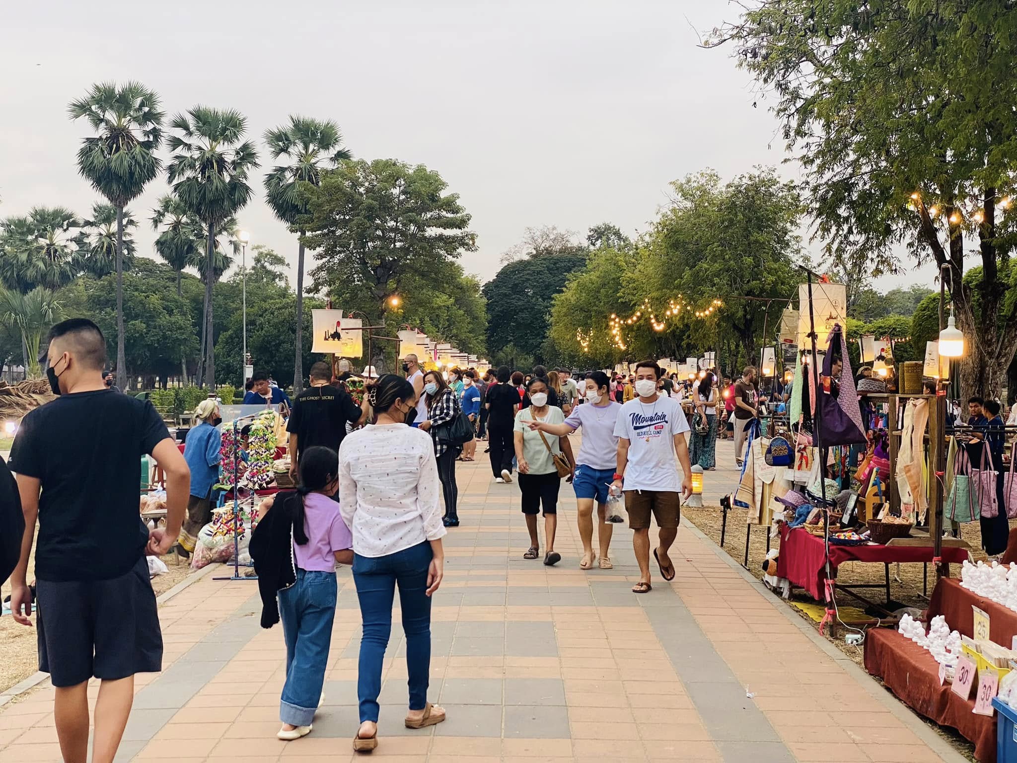 Tha Nam Rap Sadet evening market — stalls and visitors along the Sukhothai promenade