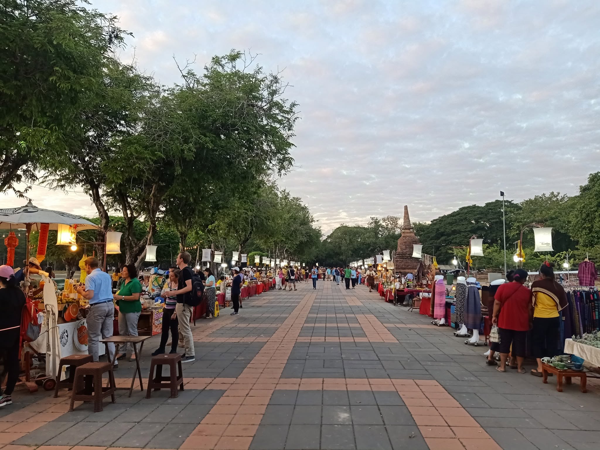 Evening market stalls along the ancient moat promenade in Sukhothai, lit by lanterns at dusk