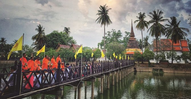 Monks receiving alms at dawn on a quiet Sukhothai street